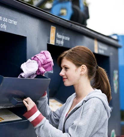 Woman dropping off used clothes in a donation bin