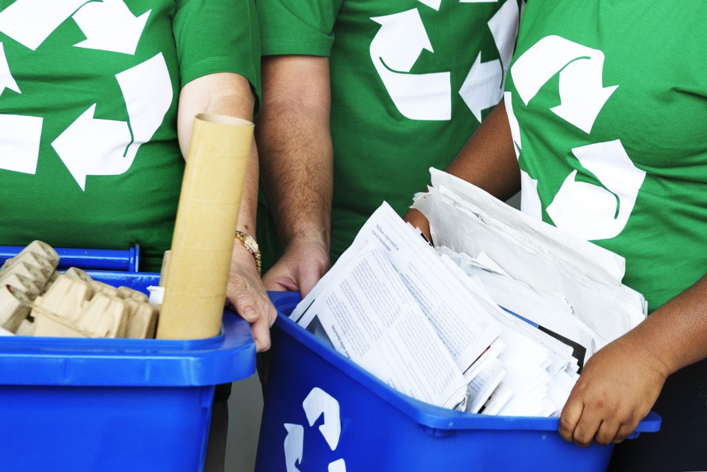 Environmentalists recycling paper products in blue bins.