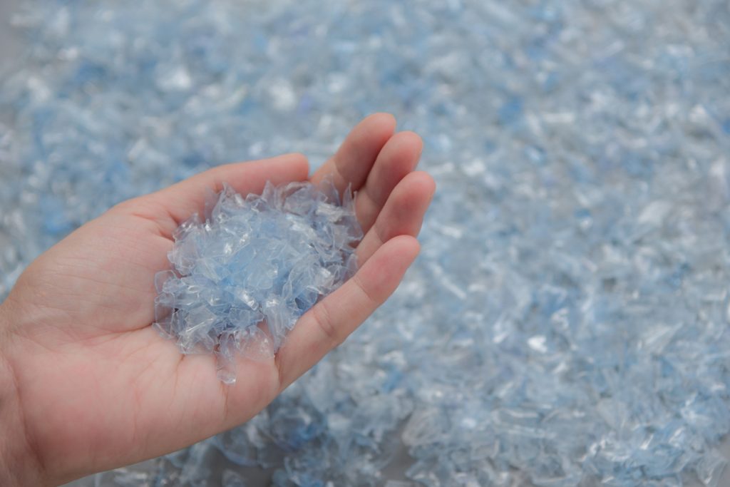 Hand holding shredded plastic for recycling