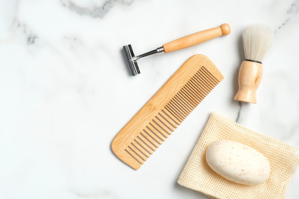 Eco-friendly wooden shaving accessories for man on marble table. Flat lay, top view. Reduce plastic waste concept