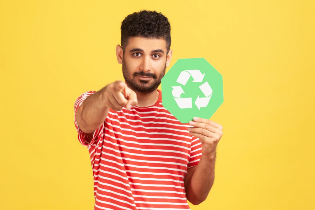 Man holding a recycling loop sign and pointing at the reader