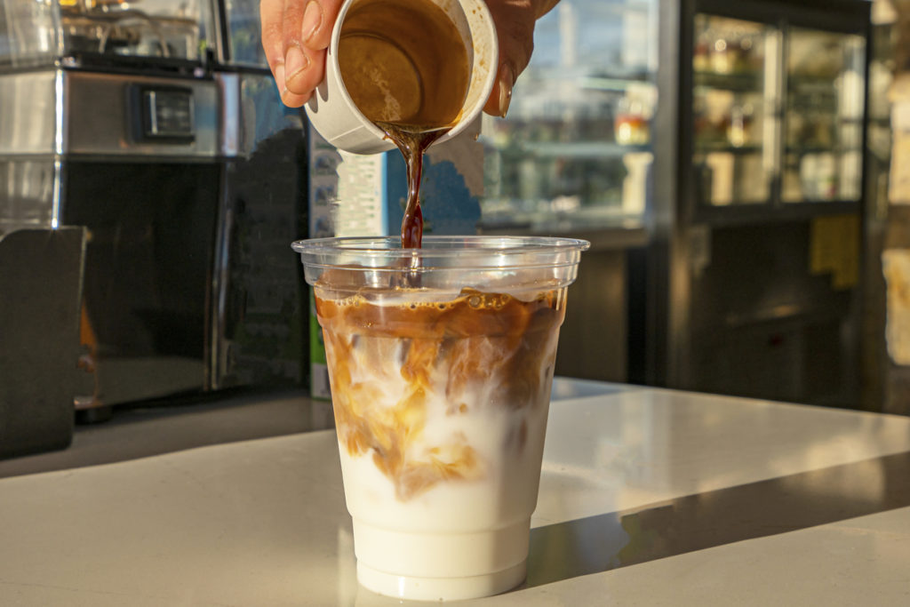 bartender is preparing iced coffee in disposable plastic cup