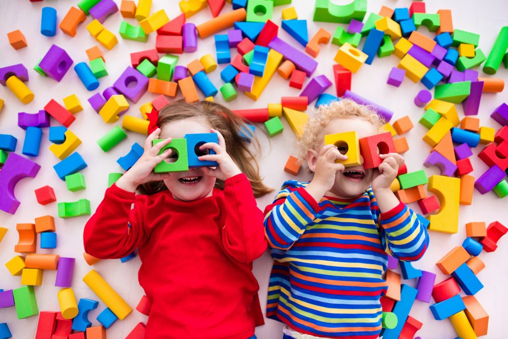 Happy preschool age children play with colorful wooden toy blocks. Top view from above. Reduce plastic waste concept