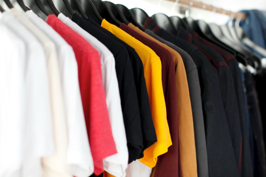 Many t-shirts in different colors hanging on the rack