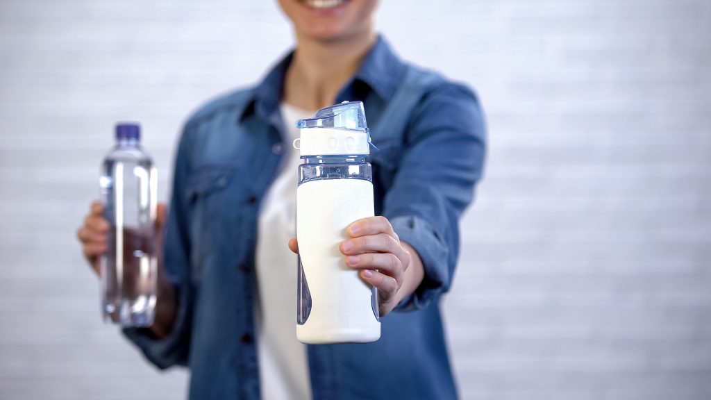 Female choosing reusable thermos instead disposable bottle, plastic pollution