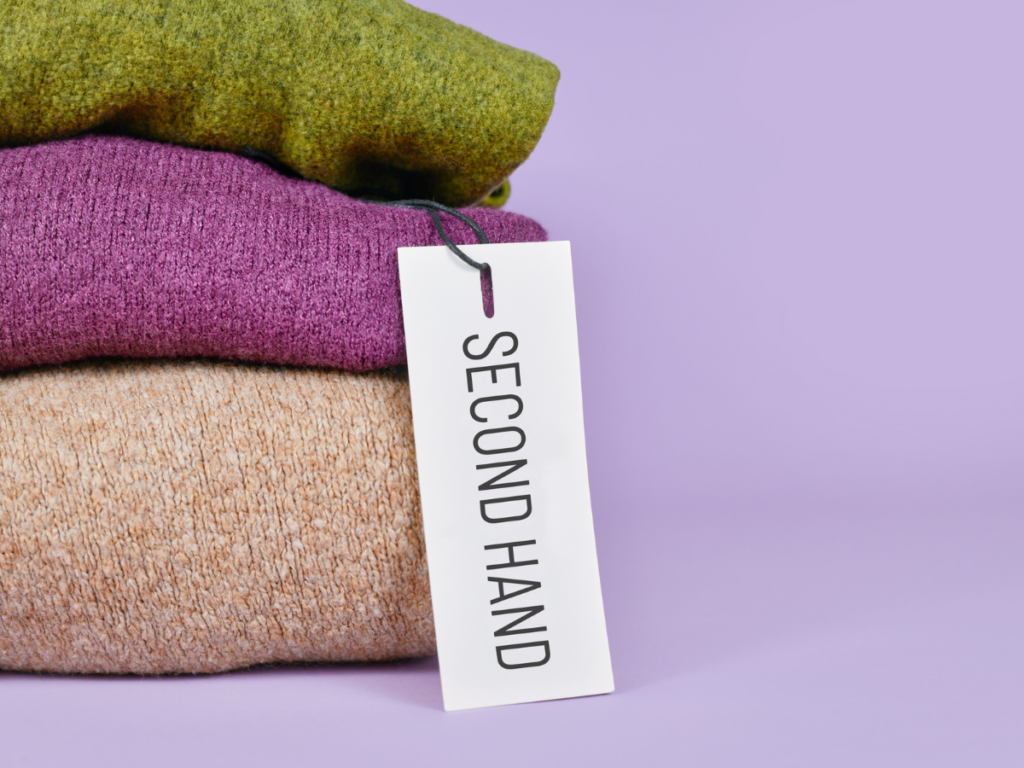 sweaters piled with a tag that says second hand