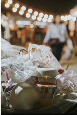 Garbage in a bin with a festival backaground