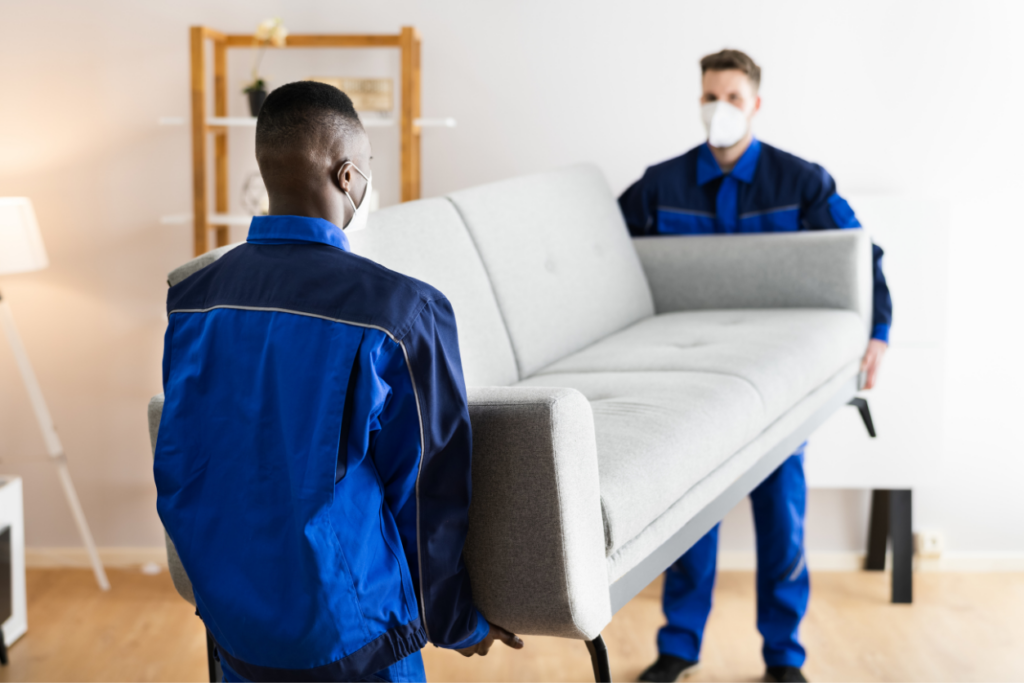 2 men carrying out a couch for donation