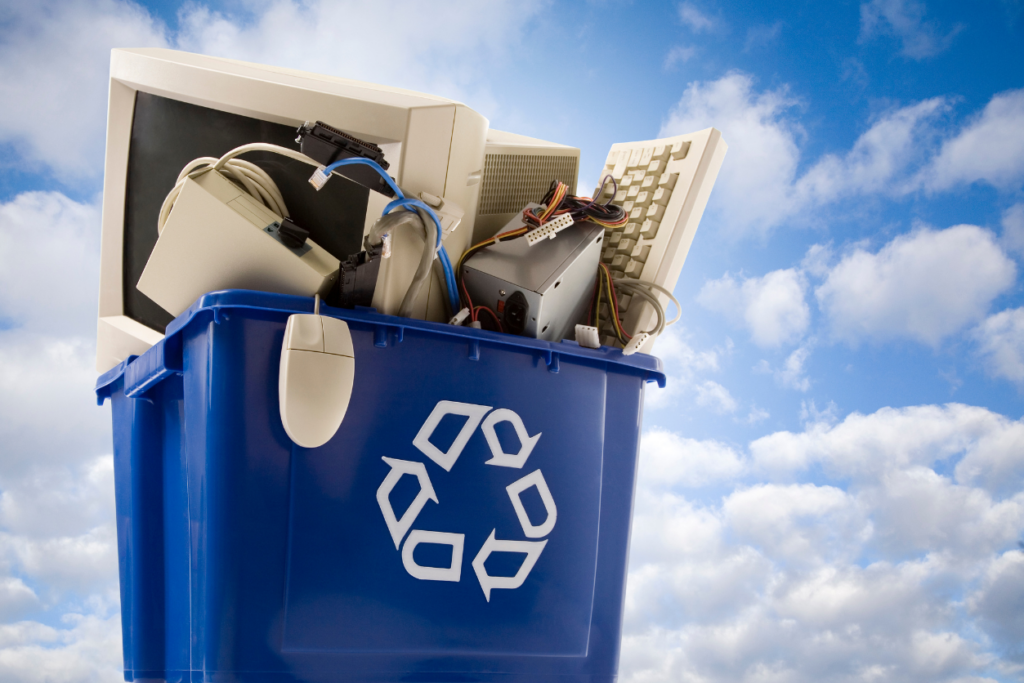 blue sky background with blue recycling bin filled with old electronics