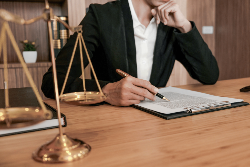 Person reading a document on a clipboard next to scales of justice indicating legislation