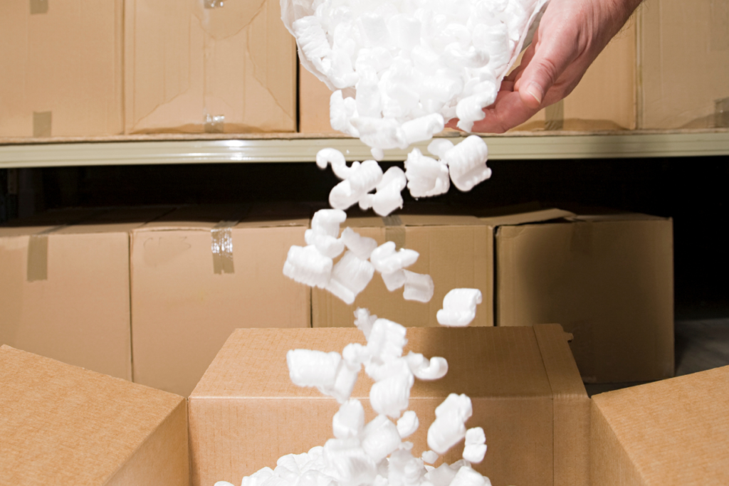 person pouring packing peanuts into another box to reuse them.