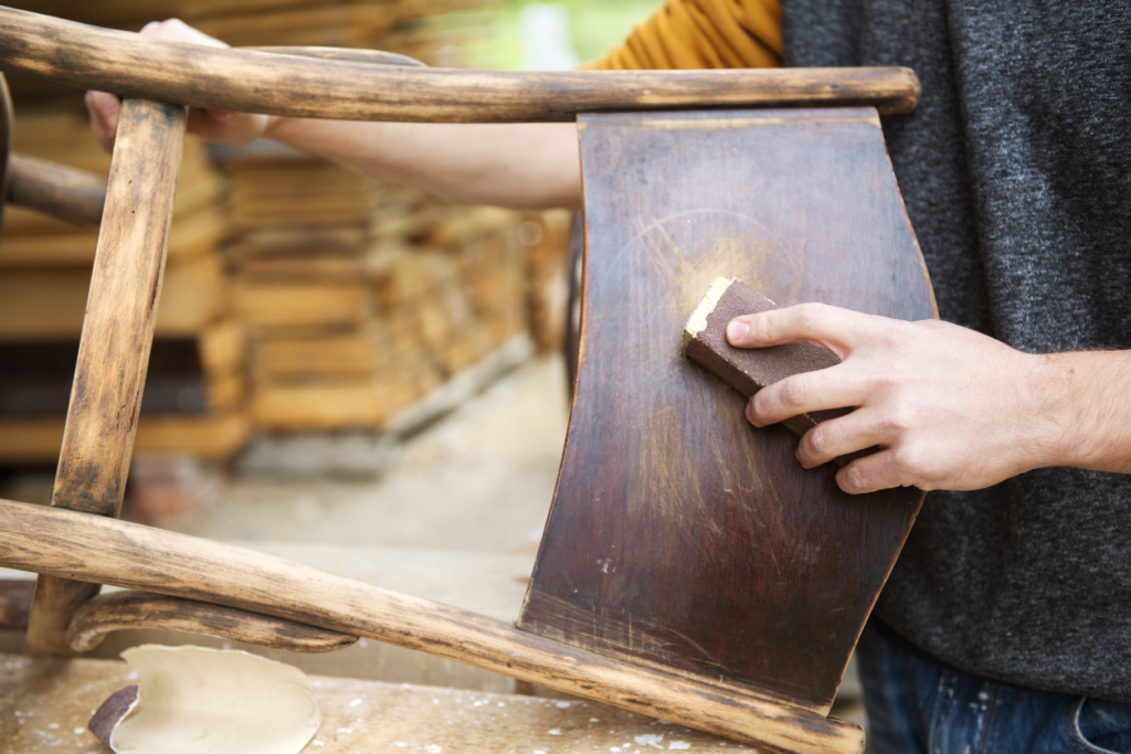 Someone sanding down an old wooden chair