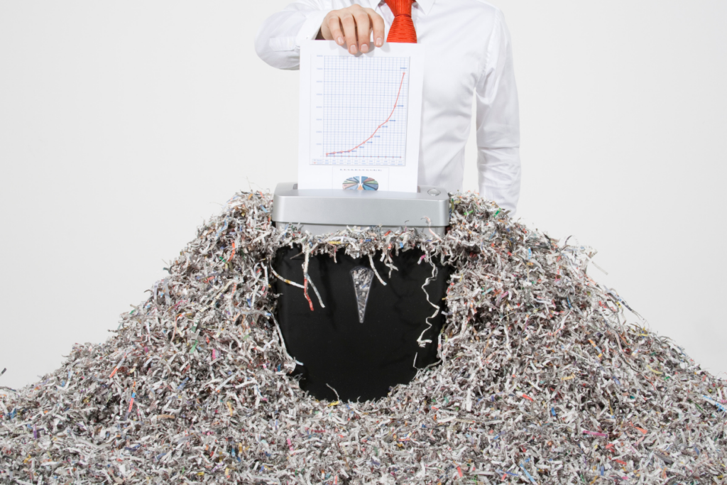 office worker shredding documents with a large pile of shredded paper around them.