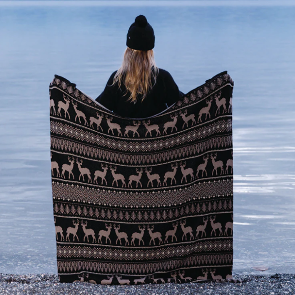 Woman holding up a throw blanket on the beach